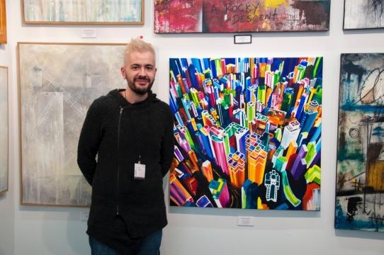 Pako standing beside one of his paintings at NYC's ArtExpo. / Photo via Pako Campo, used with permission.