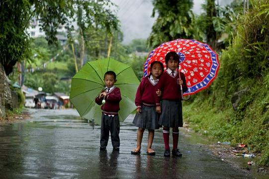 School children in the rains. - [Image credit – Ms Sarah / Wikimedia Commons]